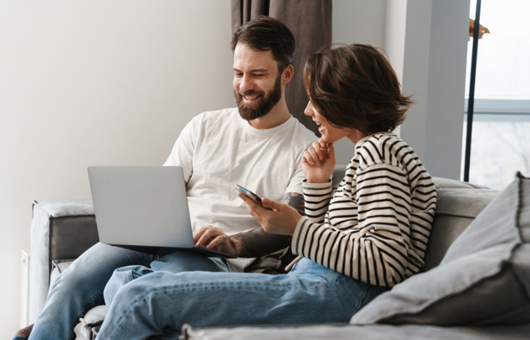 Couple on couch looking up second mortgage on computer