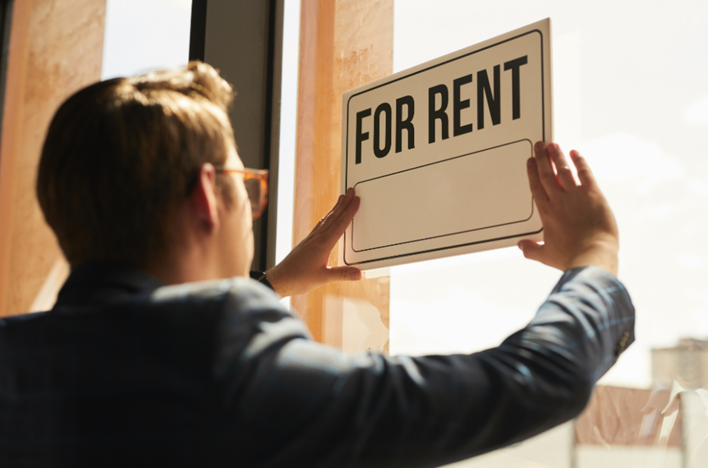 Man putting For Rent sign on window