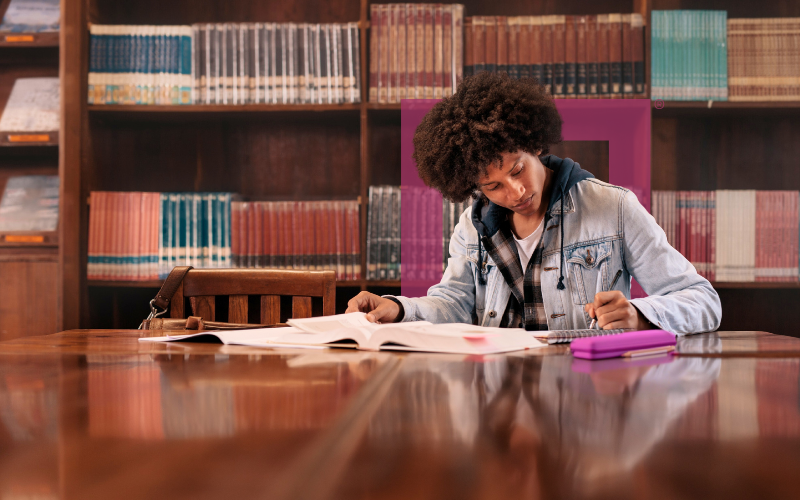 college-student-studying-in-library-with-a-magenta-pencil-case-on-desk